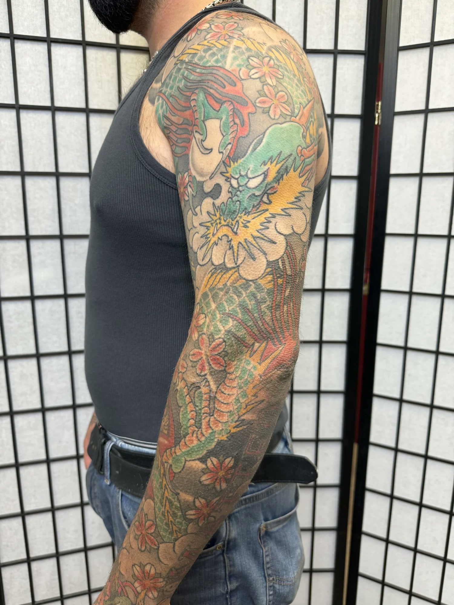 Full-colour Japanese dragon sleeve on a client wearing a clean black tank top