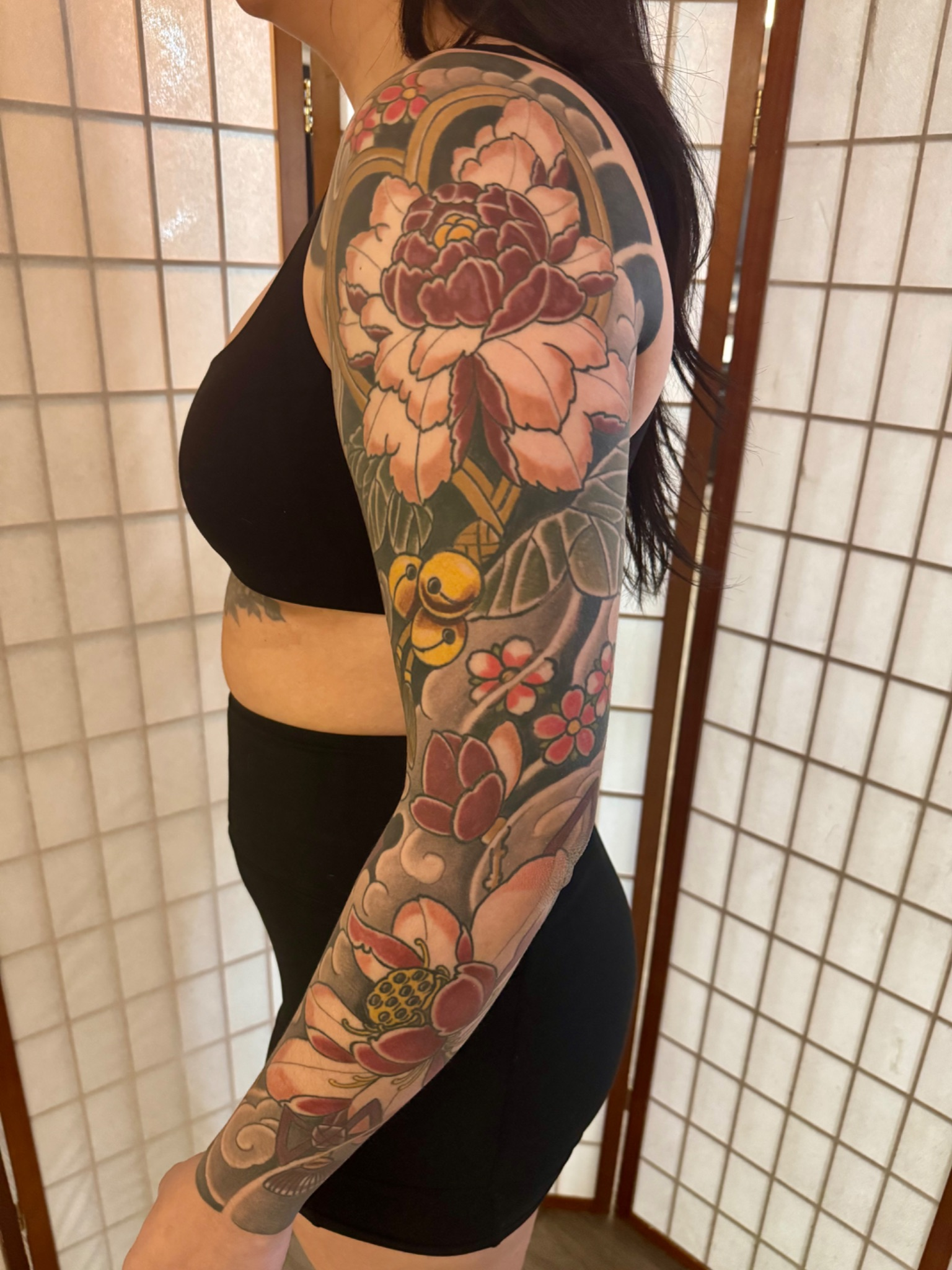 Healed full-colour Japanese peony sleeve on a client wearing black